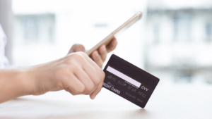 Hand holding a credit card, signaling the influence of shifting consumer behaviors on reshaping trade show dynamics as commerce increasingly moves towards digital platforms.