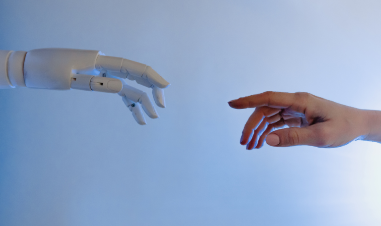 Human hand reaching out to robot hand, symbolizing humans & technology working together.